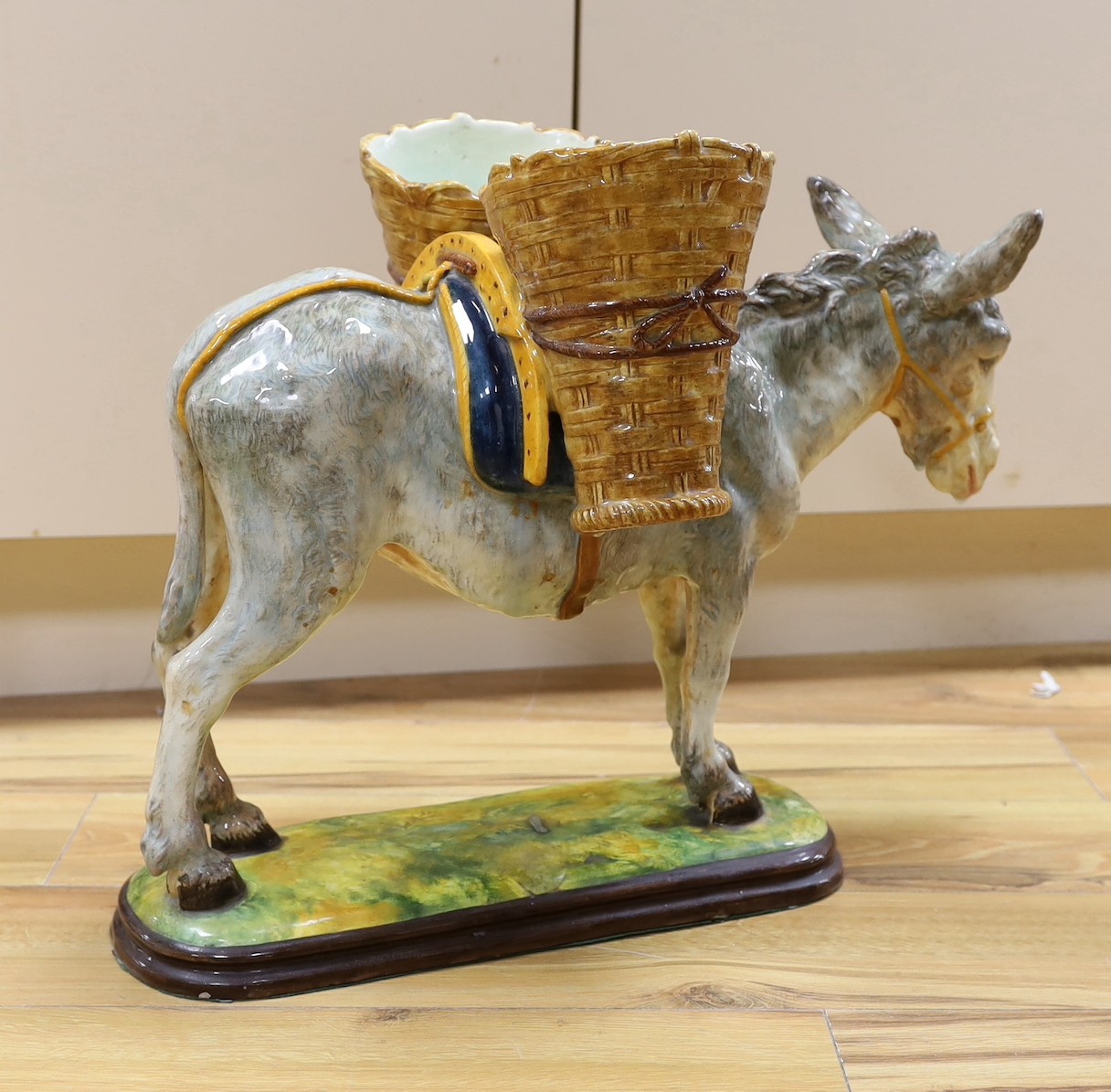 A large 20th century Italian maiolica model of a donkey with basket work panniers - 56cm long